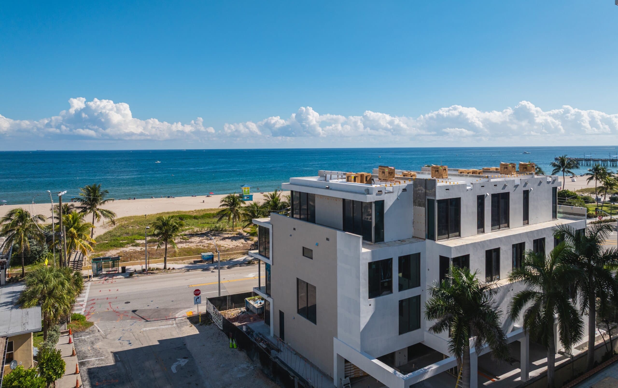 Aerial photo of the Finesse townhomes under construction across from the ocean, with the pier beyond